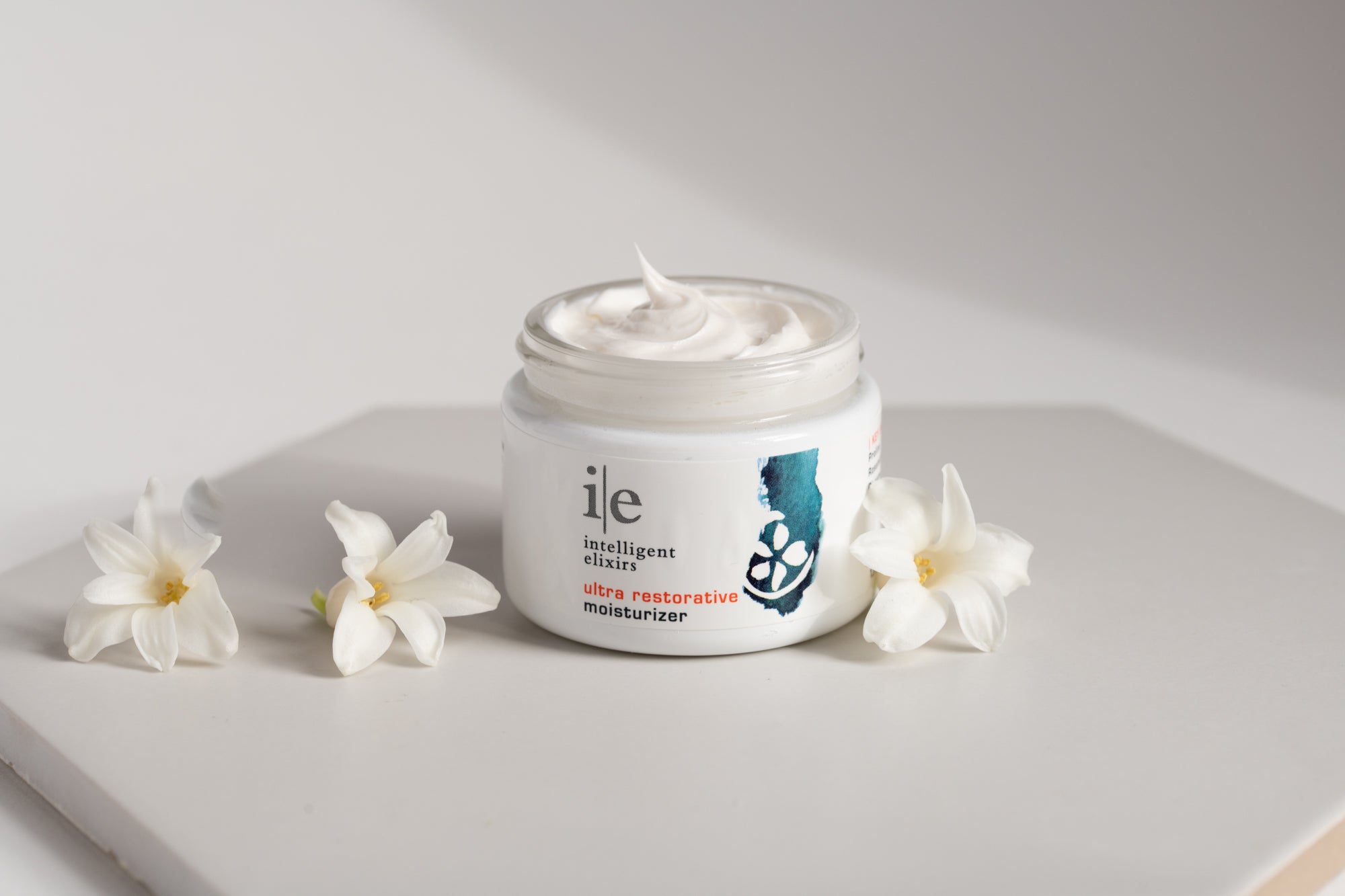 Ultra Restorative Facial Moisturizer on a counter with flower petals